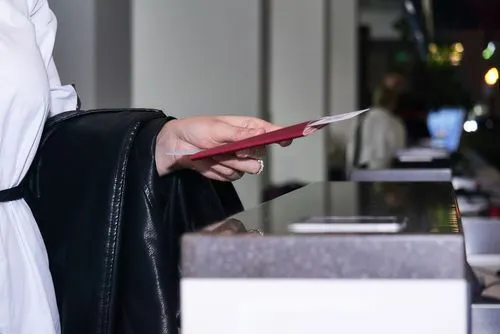 Una persona entregando un pasaporte y documentos de viaje en un mostrador de aeropuerto o punto de control de inmigración.