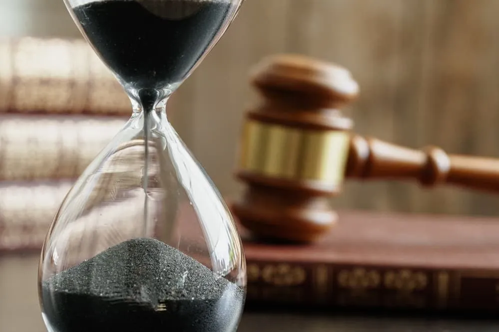 Reloj de arena y mazo de juez sobre la mesa de cerca - Concepto de plazos legales