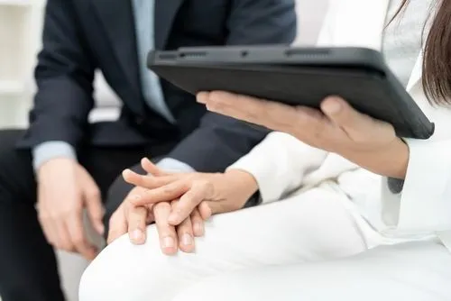 A professional holds a tablet while gently placing a reassuring hand on a colleague’s hand.