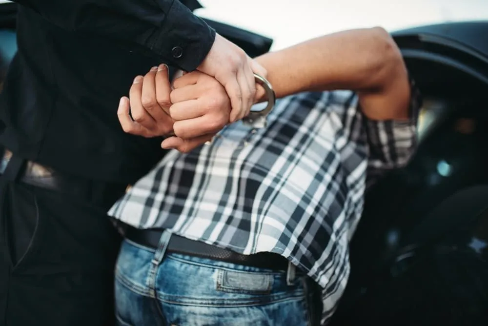 Un agente de policía arresta a un ladrón de autos en la calle.