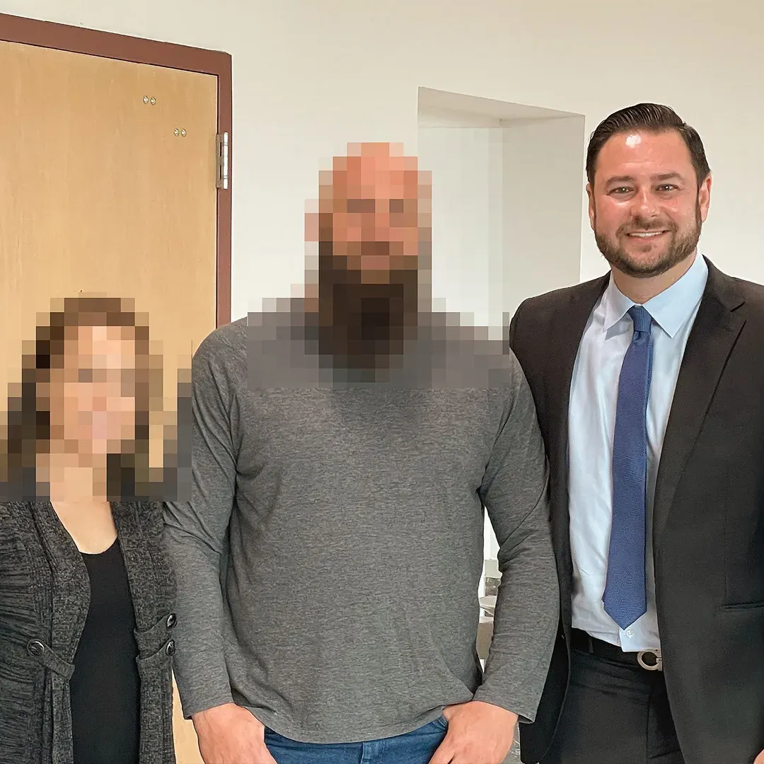 Adam Rossen standing with two people, their faces blurred for privacy