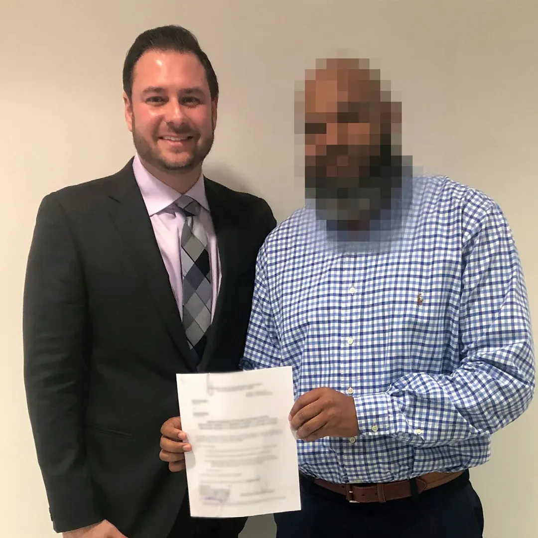 Adam Rossen with a client holding a document, the client’s face blurred for privacy