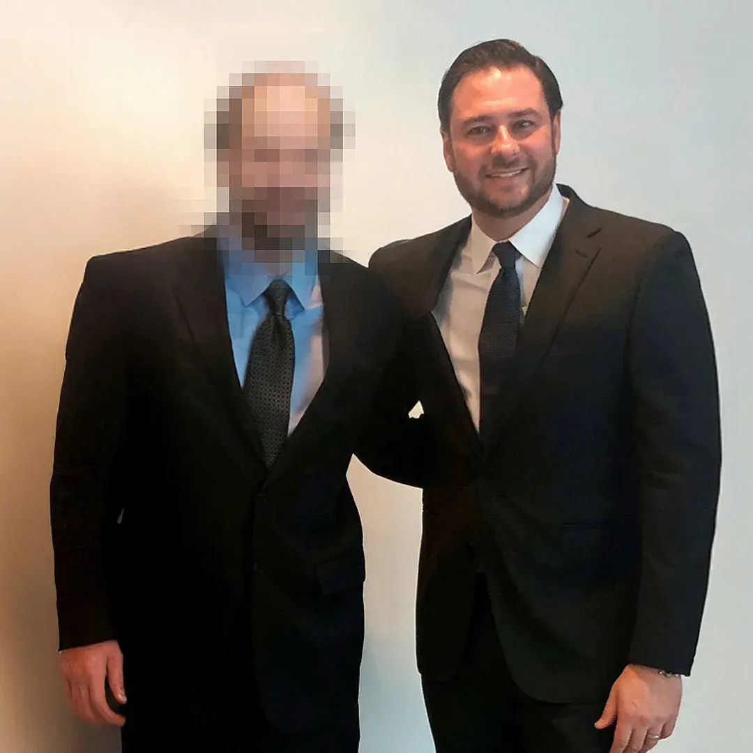 Adam Rossen with a client in a suit, the client’s face blurred for privacy