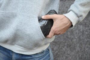 Traficante de drogas sacando una bolsa de cocaína de su sudadera con capucha