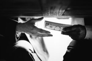 Persona entregando dinero por debajo de la mesa