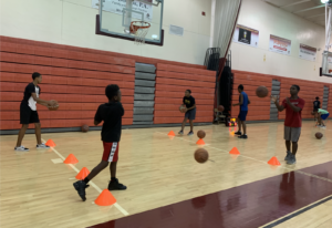 Adam Rossen and a PBSO Deputy running basketball drills with children at the Tri-City Basketball, Academics and Mentoring Camp
