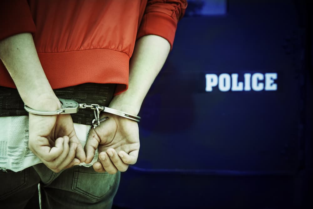 A man is handcuffed and arrested by police officers — a concept of law enforcement, detention, and criminal justice.