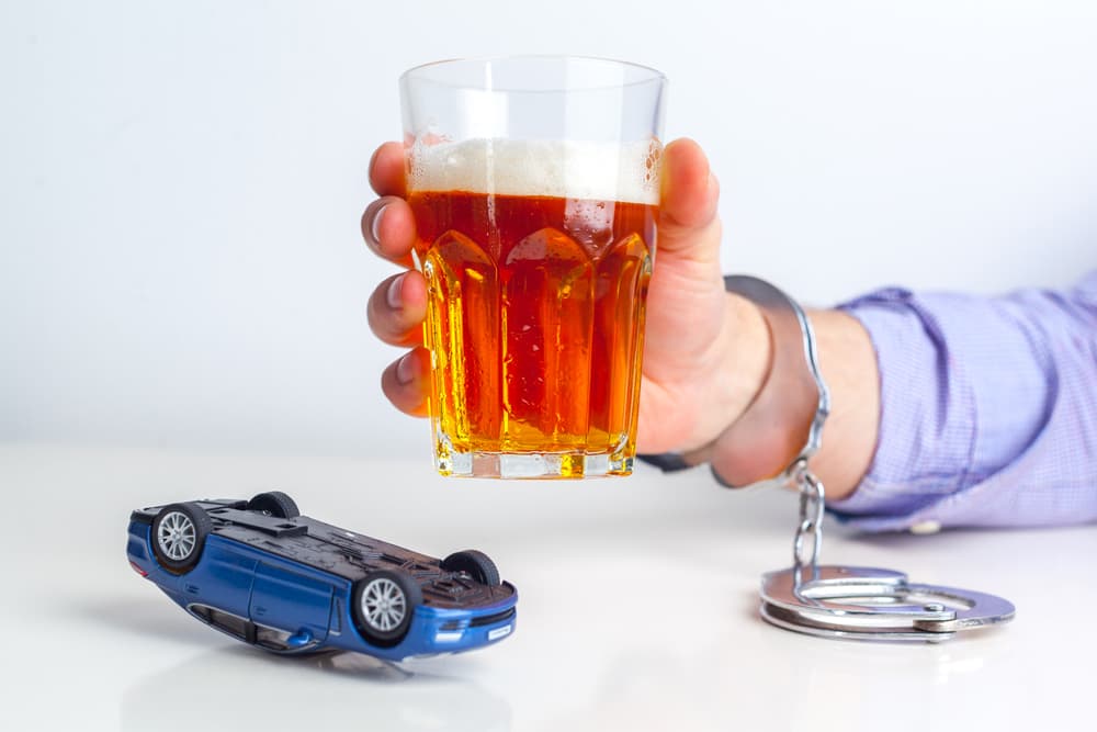 Drunk Driving Concept – Alcohol bottle, car keys, and handcuffs symbolizing DUI consequences and impaired driving dangers.