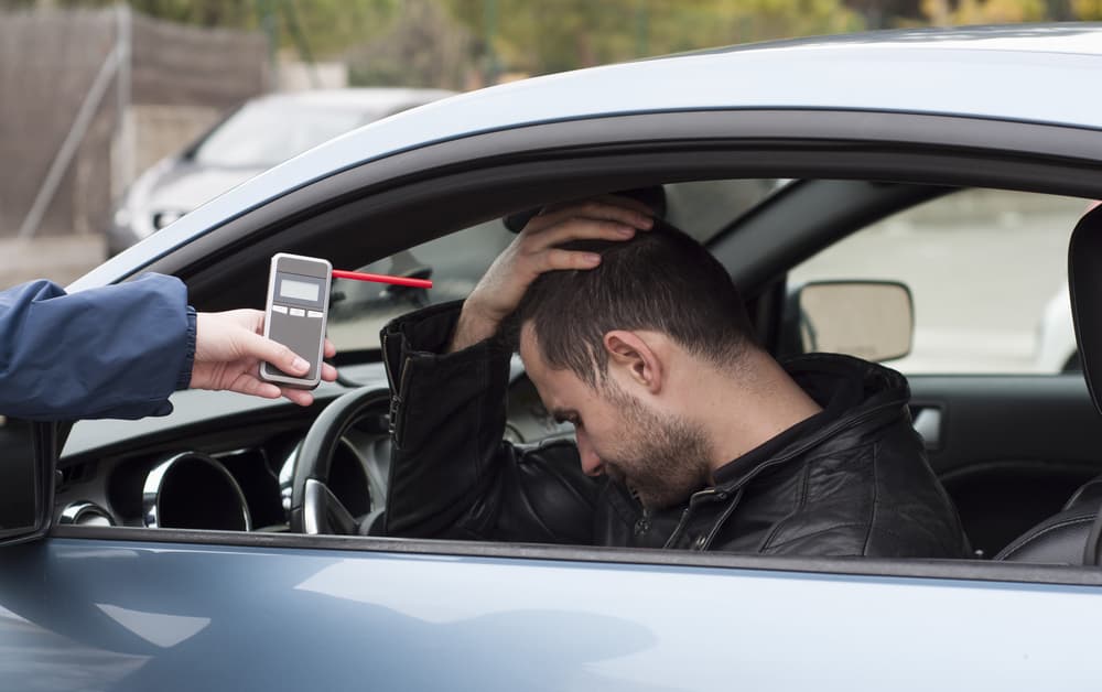 A devastated driver faces a breathalyzer test after crashing while drinking and driving—highlighting the serious consequences of impaired driving.