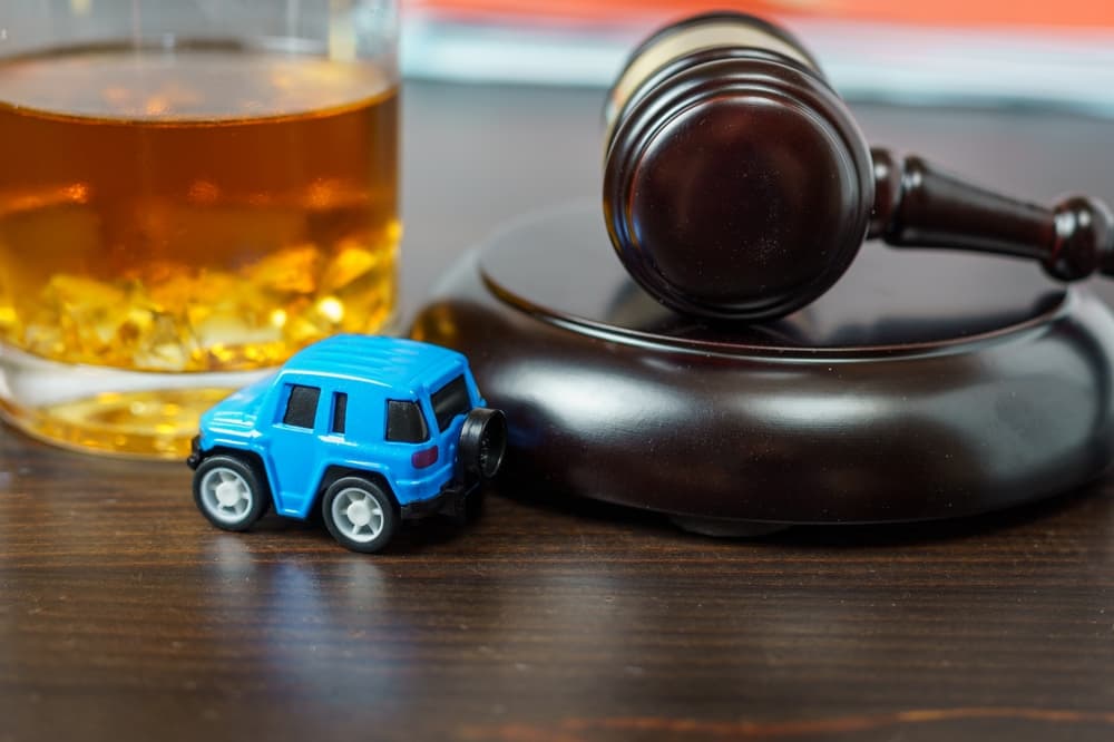 Judge's mace on a table in a court of law, glass of whiskey and miniature car. 
